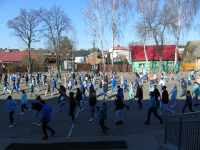 Uczniowie i nauczyciele tańczą na boisku