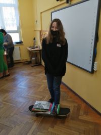 Dziewczynka pokazuje książki na deskorolce