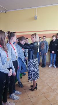 Dyrektor zawiesza medal na szyi dziewczyny