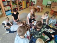 dzieci siedzą na dywanie oglądają książki