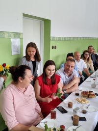 Kobiety i mężczyźni siedzą przy stole z ciastem i kawą