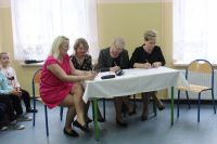 Cztery kobiety siedzą przy stole, w rękach mają długopisy
