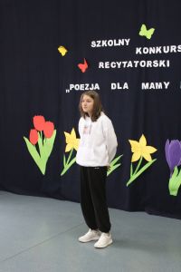 Czarnowłosa dziewczyna w białej bluzie i czarnych spodniach