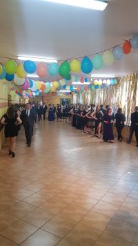 Ósmoklasiści tańczą, sala przyozdobiona kolorowymi balonami