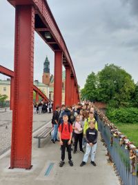 Uczniowie idą przez most. Na barierkach wiszą kłódki miłości