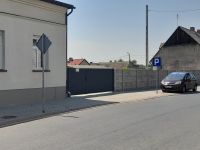Budynek, za nim brama wjazdowa na parking