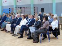 grupa ludzi siedzi w rzędach na sali sportowej