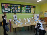 kilkoro dzieci w sali informatycznej stoi przy robocie do programowania